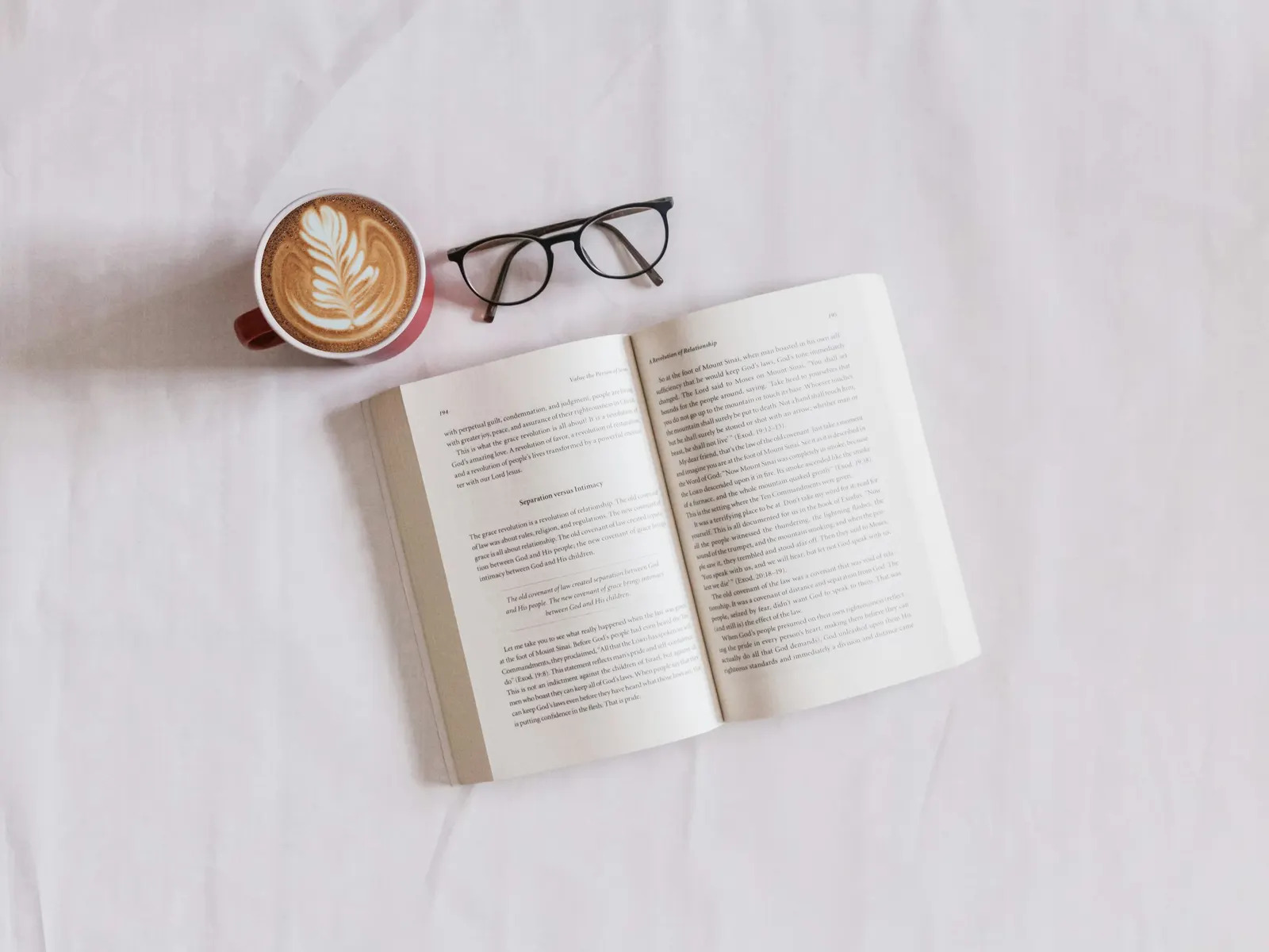 Cappuccino, reading glasses and an open book