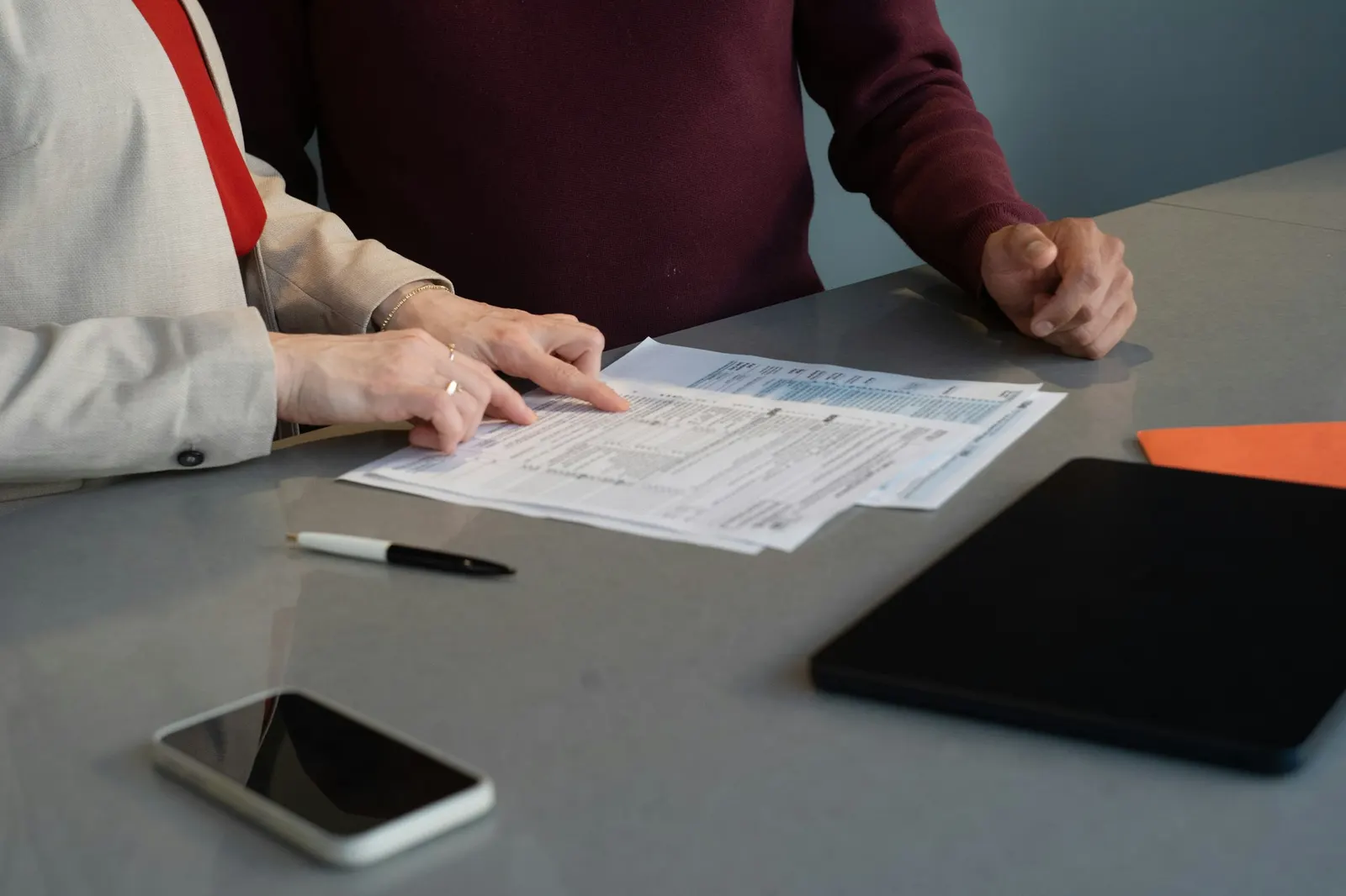 Two people comparing printed plan documents at a table