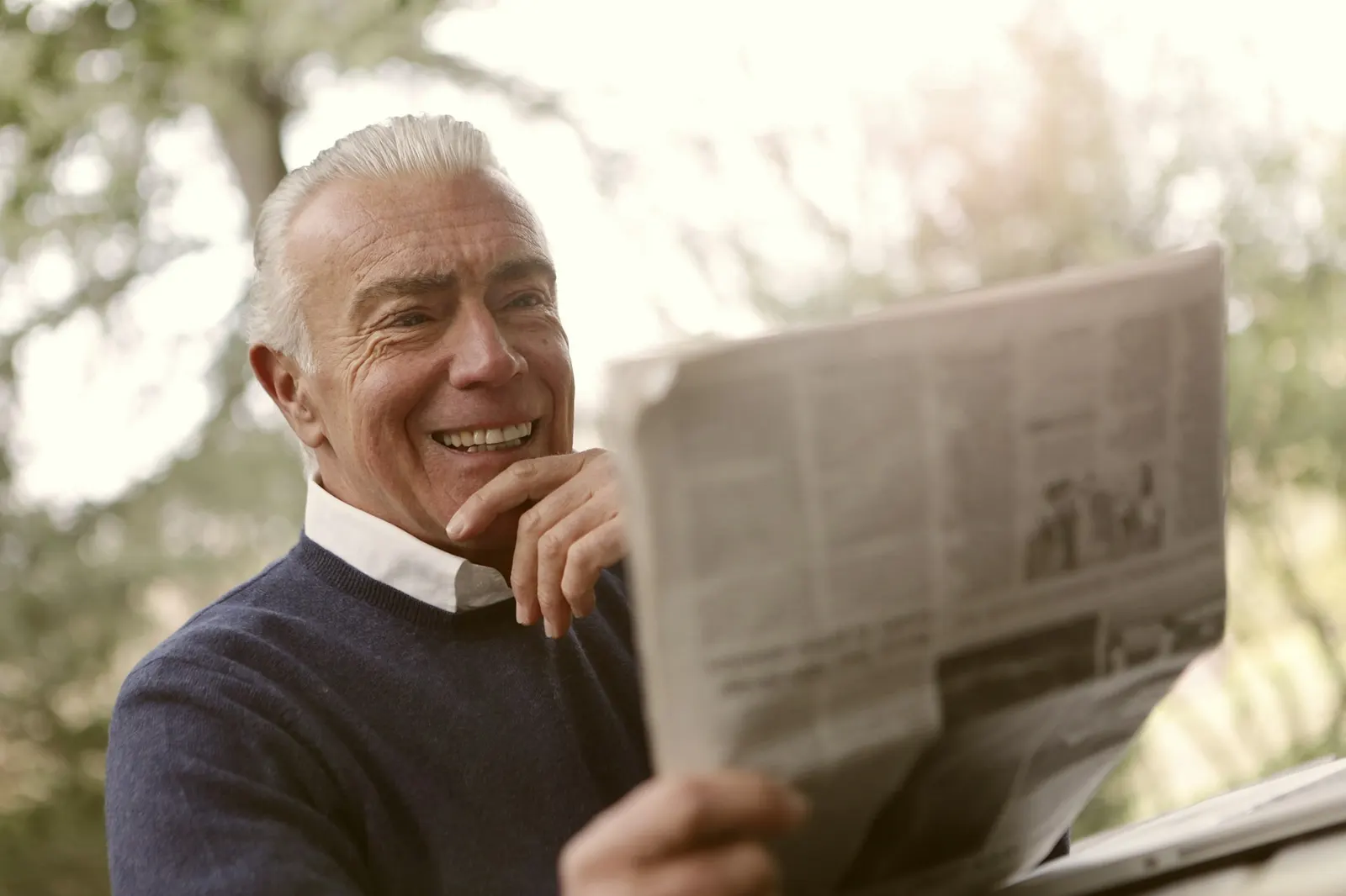 Man smiling while reading the newspaper